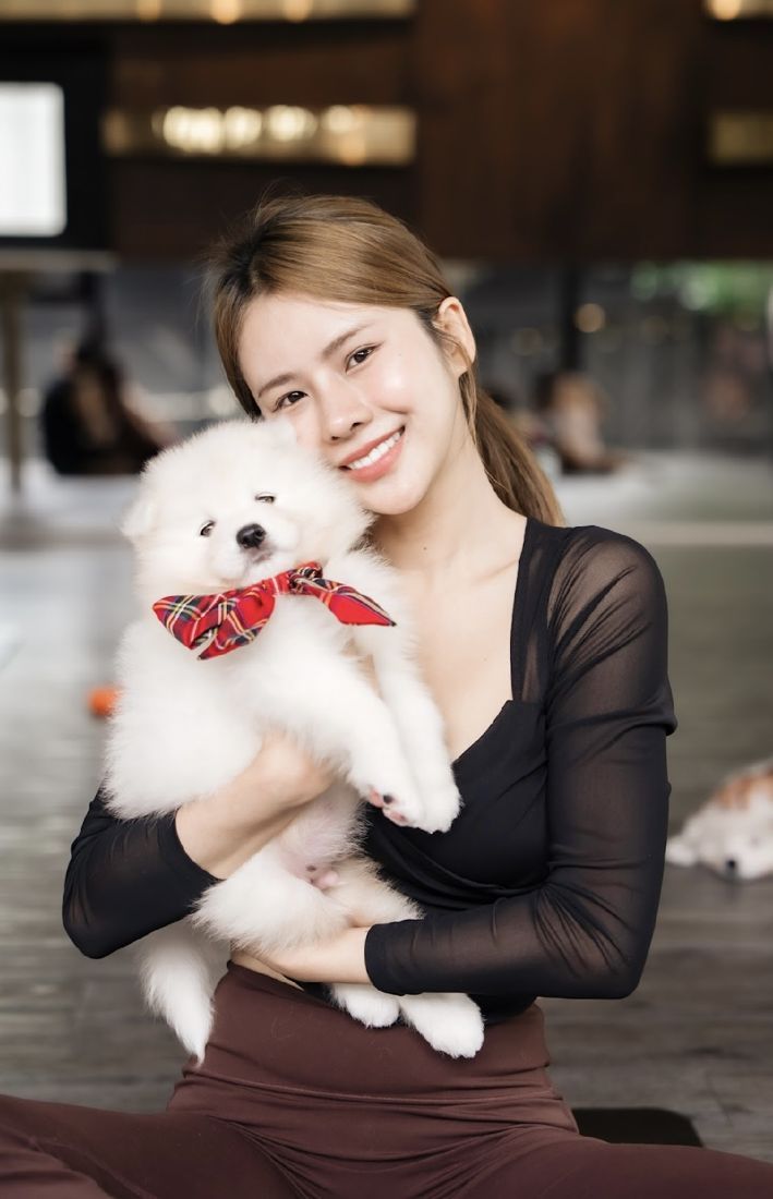 Guest hugging a samoyed puppy with a red bow