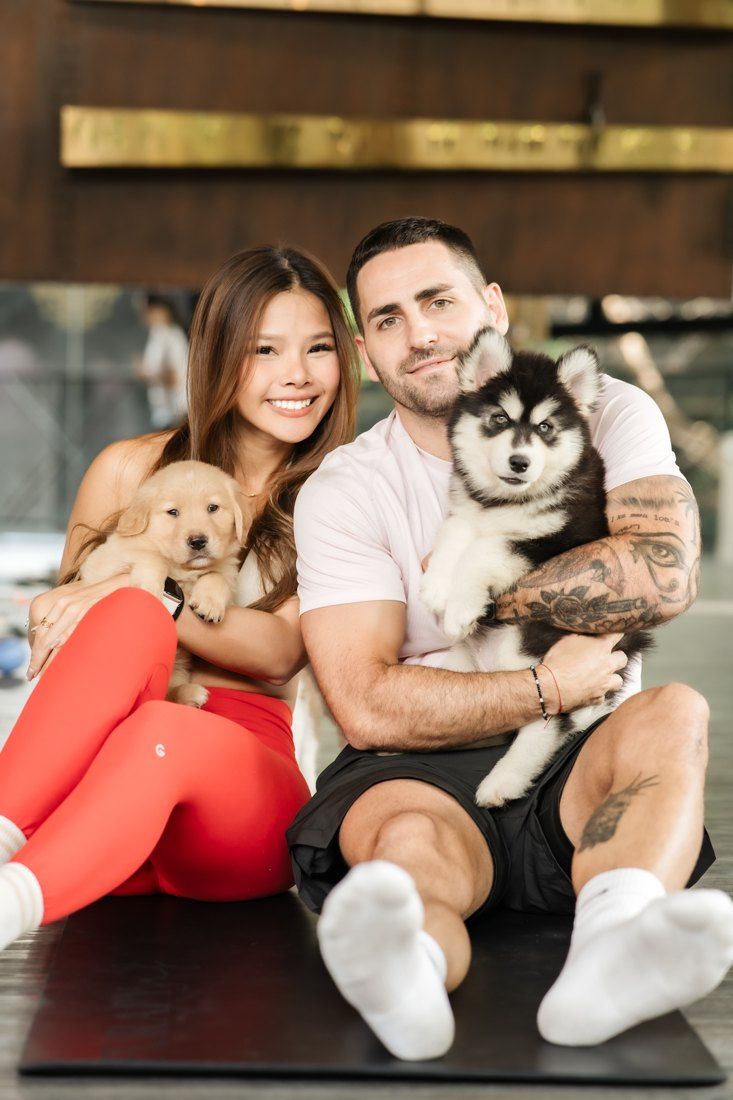 Couple holding golden and husky puppies