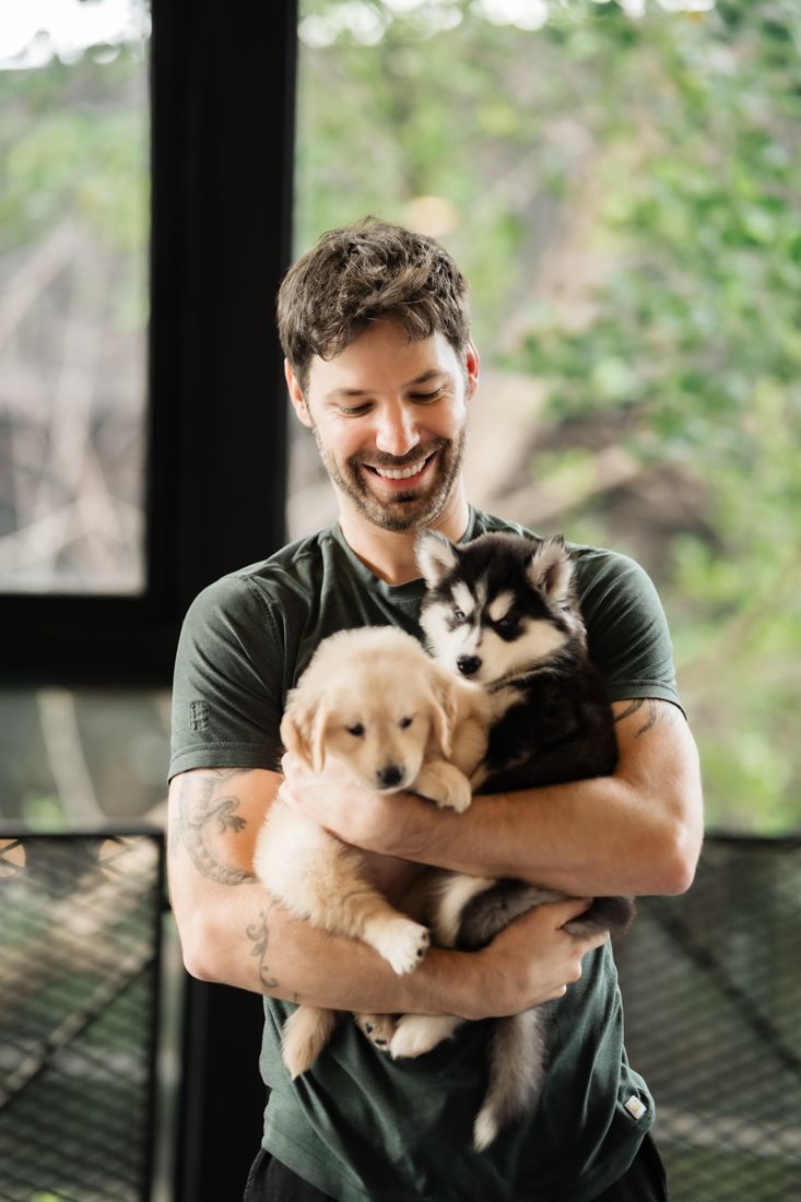 Guest holding a golden retriever and a husky puppy