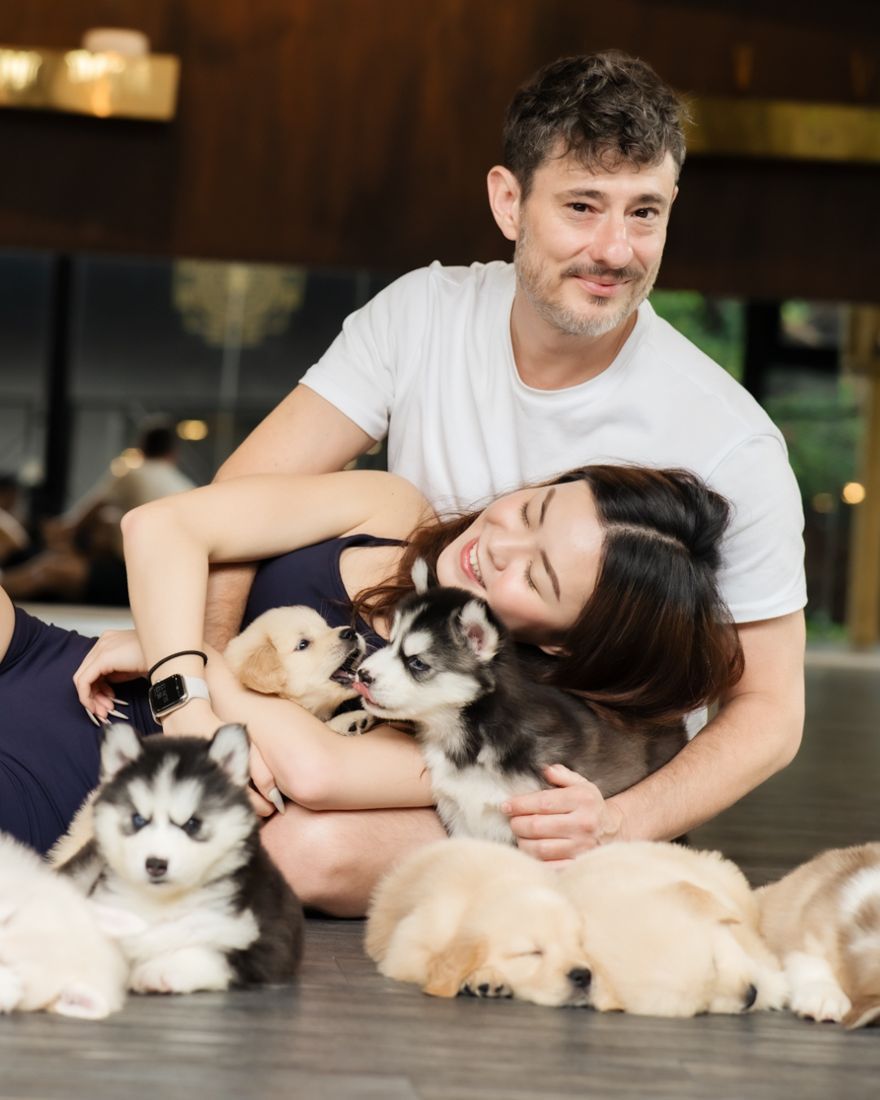 Couple lying with husky and golden puppies