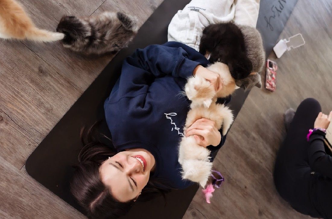 Becky Armstrong cuddling kittens on a yoga mat at Furapy