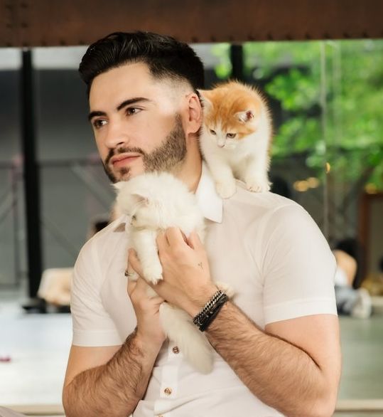 Guest holding a white kitten with a ginger kitten on his shoulder