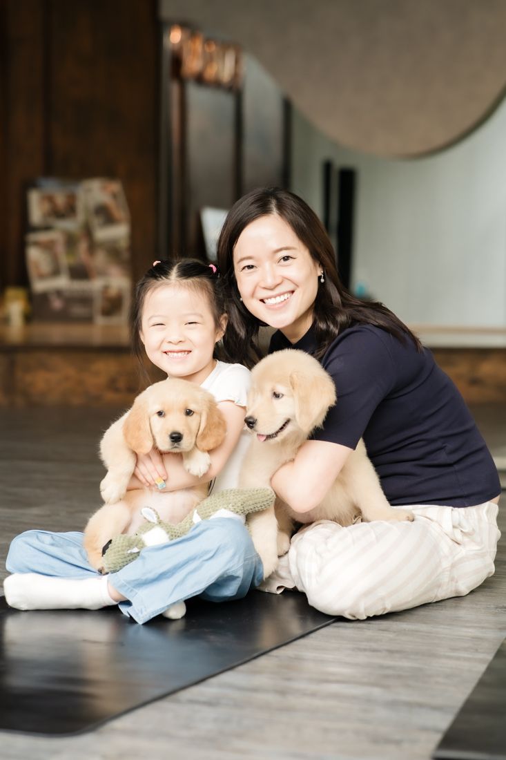 Mother and daughter with two golden retriever puppies